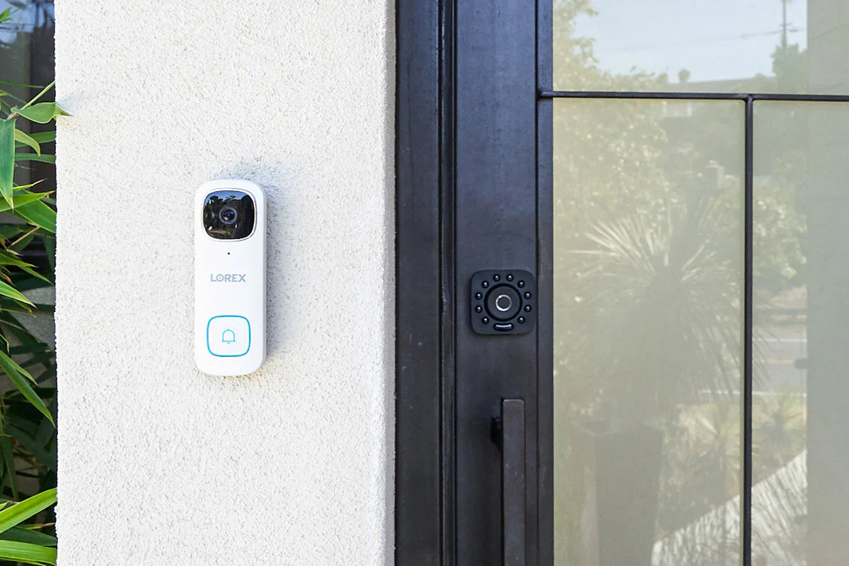 Smart doorbell attached to a house exterior next to a glass door.